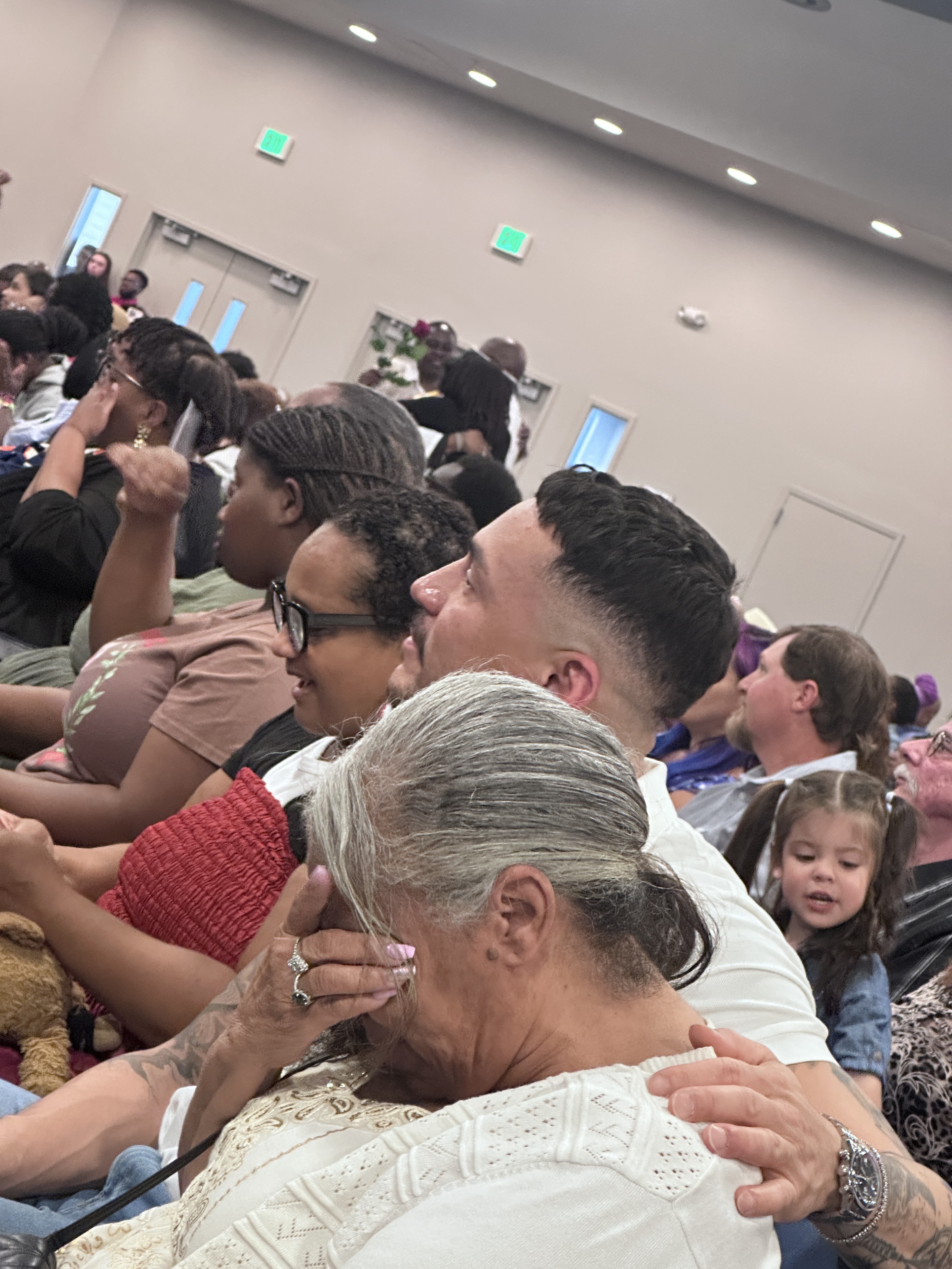 Family gathered at a graduation ceremony sharing a close embrace.